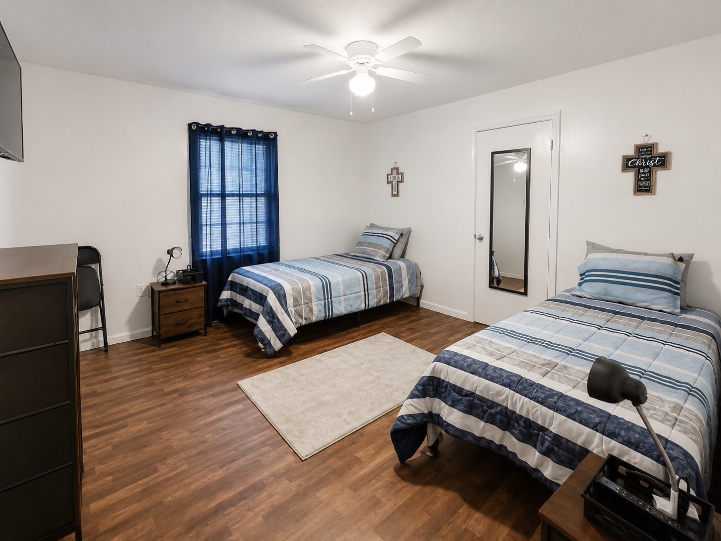 Shared bedroom with two neatly prepared beds and natural wood flooring